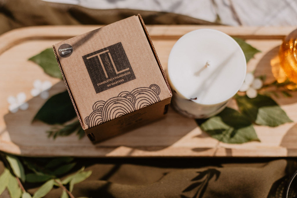 4. Top view of TL Candles box and white soy wax candle on wooden tray with leaves