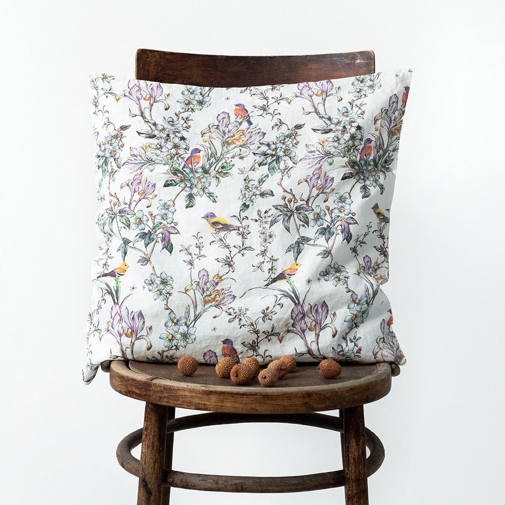 9. Bird and floral print Linen Tales cushion cover on a wooden chair with small decorative nuts