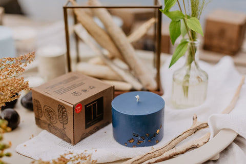 5. TL Candles hand-made blue soy wax candle with amber pieces, displayed with packaging and decor on a table