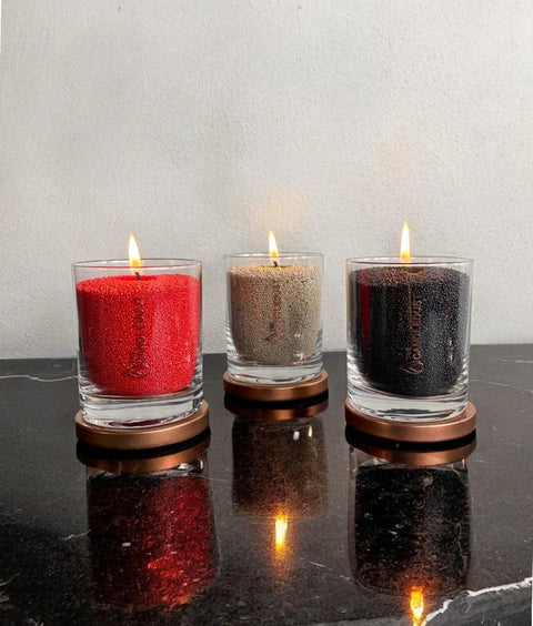 4. Trio of Candledust powder candles in red, beige, and black, each in glass with flames