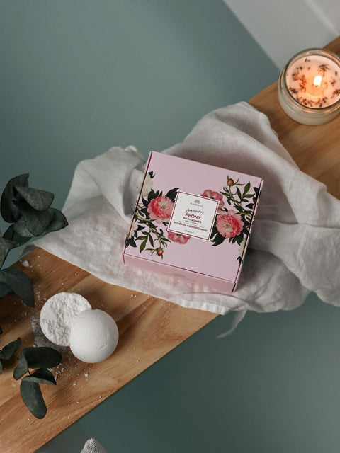 4. Lifestyle image of Magrada Peony Bath Bomb set on wooden bath tray with candle and eucalyptus, creating a relaxing ambiance