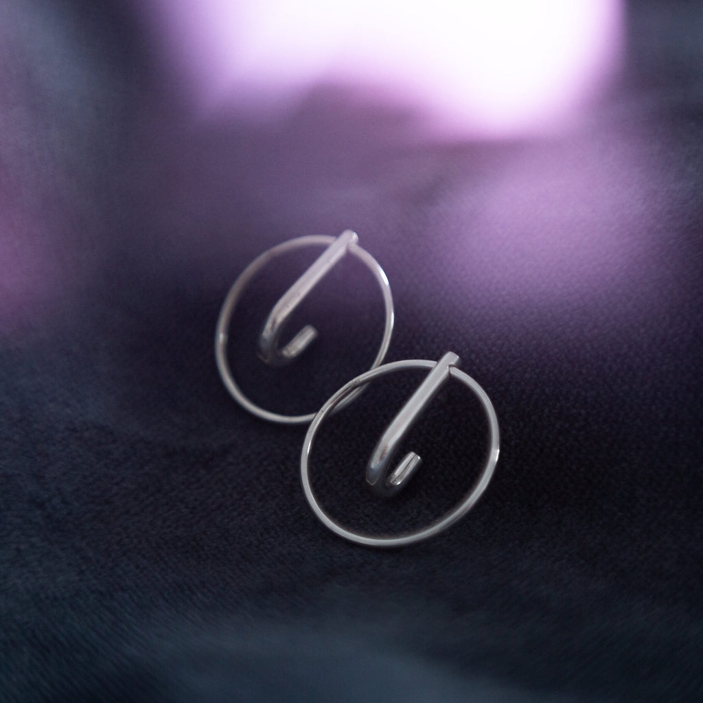 3. Close-up of Maarja Palu LAYERS x1 silver earrings on dark fabric, showing minimalist design