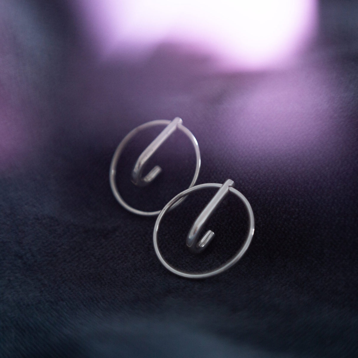 3. Close-up of Maarja Palu LAYERS x1 silver earrings on dark fabric, showing minimalist design