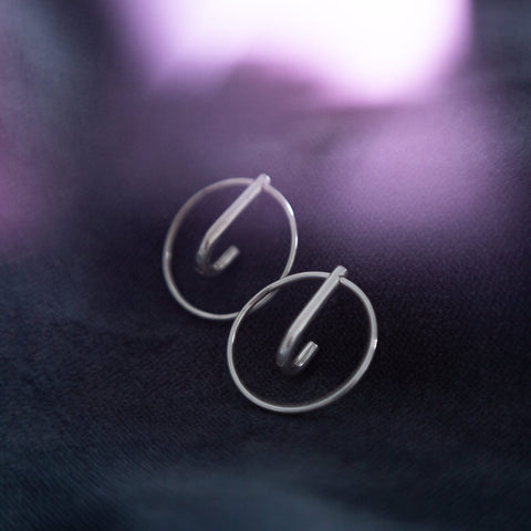 3. Close-up of Maarja Palu LAYERS x1 silver earrings on dark fabric, showing minimalist design