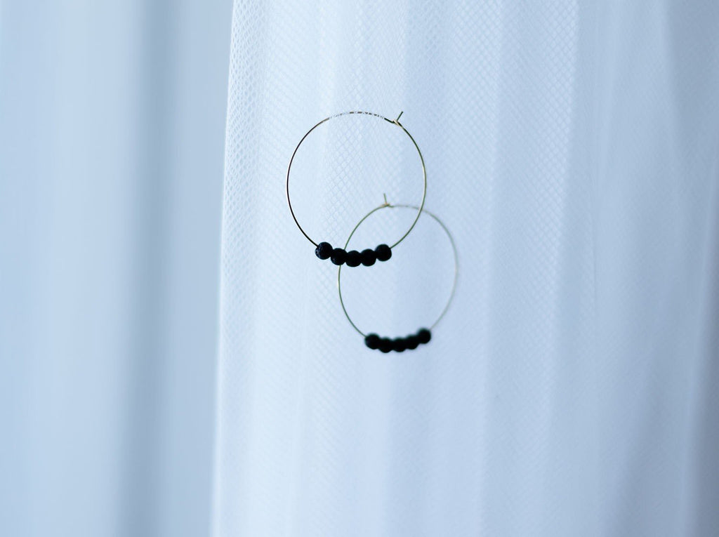 2. 14K gold plated diffuser earrings with black lava beads by Canary Lava, shown against a white fabric background