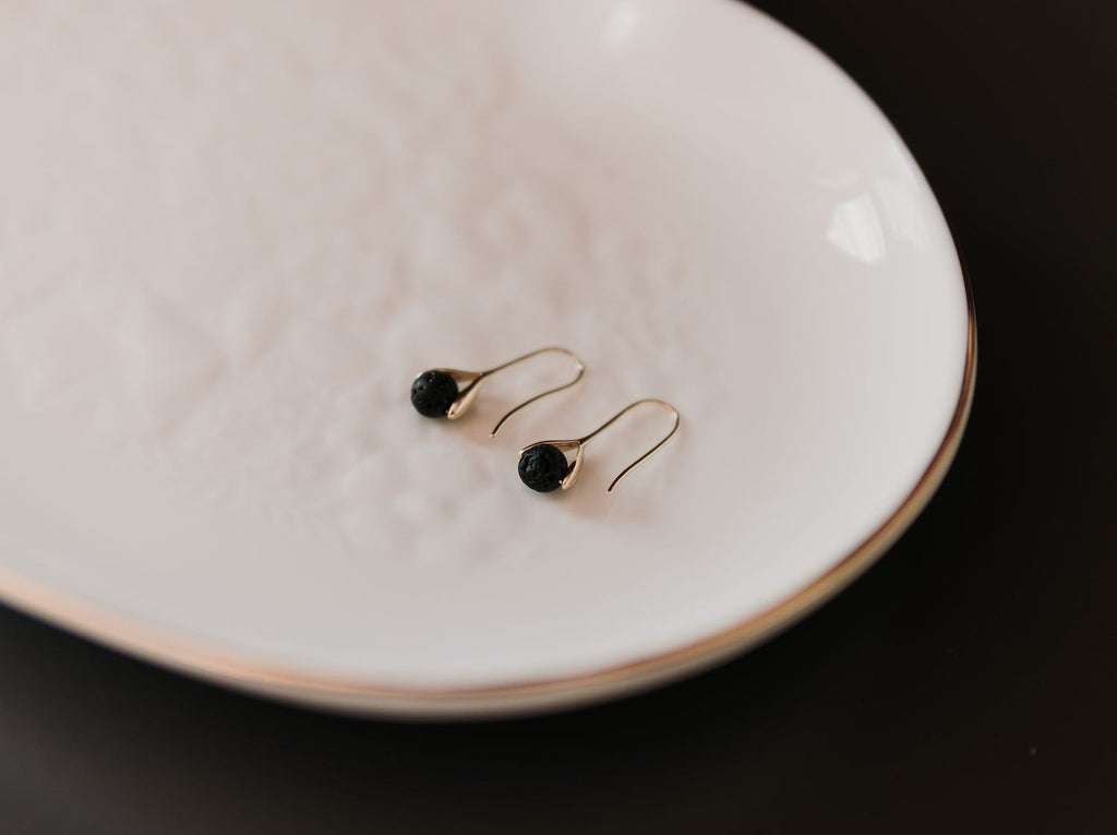 3. Close-up of Canary Lava 14K gold-plated diffuser earrings with lava beads on white plate