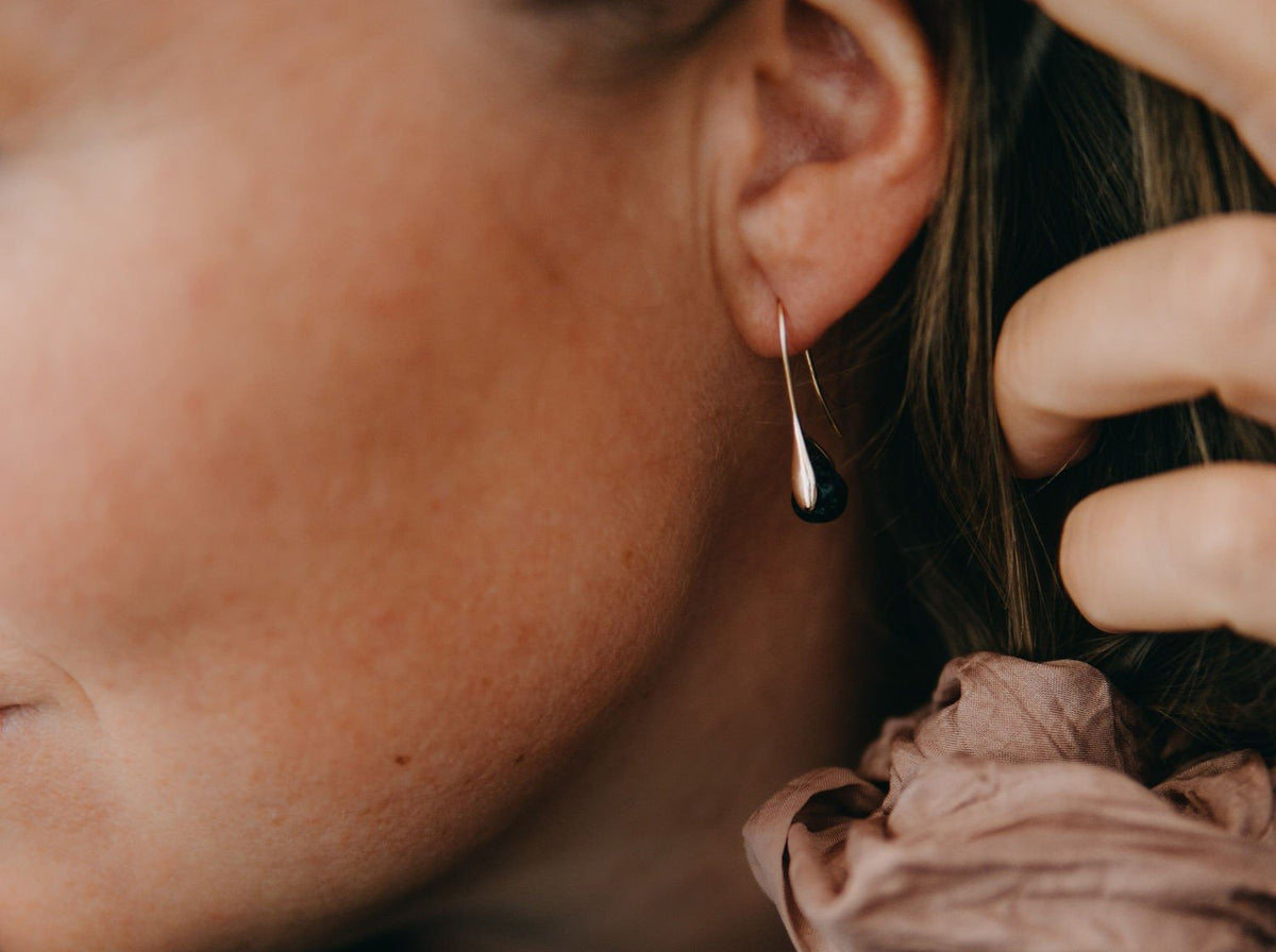 1. Woman wearing Canary Lava 14K gold-plated diffuser earrings with lava bead, shown in lifestyle setting