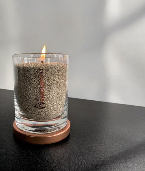 3. Unscented olive green powder candle by Candledust in glass, lit on a dark surface