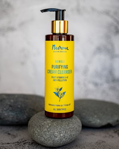 4. Nurme Neroli Purifying Cream Cleanser bottle on stones, emphasizing natural ingredients