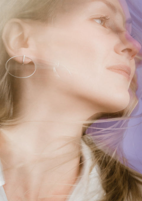 1. Woman wearing Maarja Palu LAYERS x2 silver earrings, showcasing minimalist design with interlocking circles