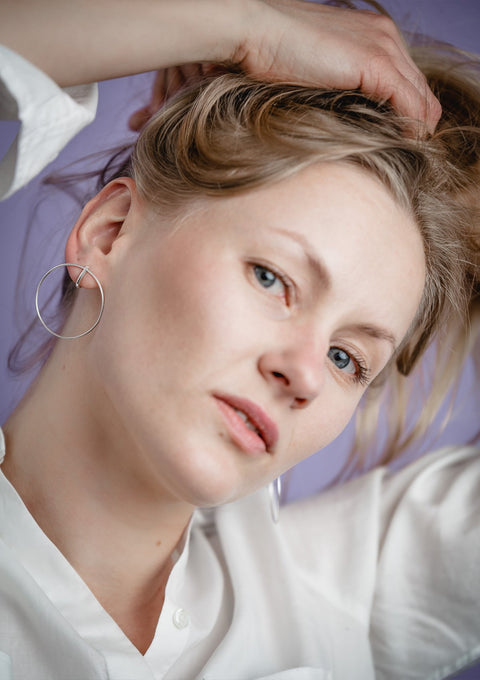 2. Woman styling hair while wearing Maarja Palu LAYERS x2 silver earrings, highlighting elegant geometric design