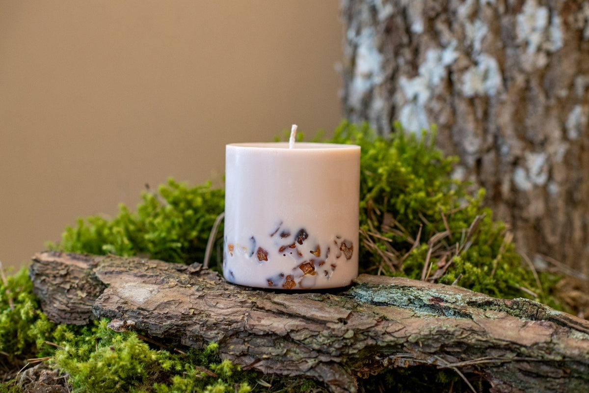 10. TL Candles hand-made soy wax candle with amber pieces, displayed on mossy wood in a natural setting