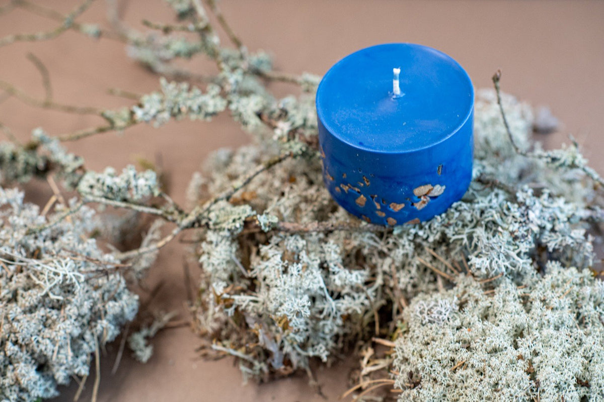 9. TL Candles hand-made blue soy wax candle with amber pieces, shown on natural moss and branches