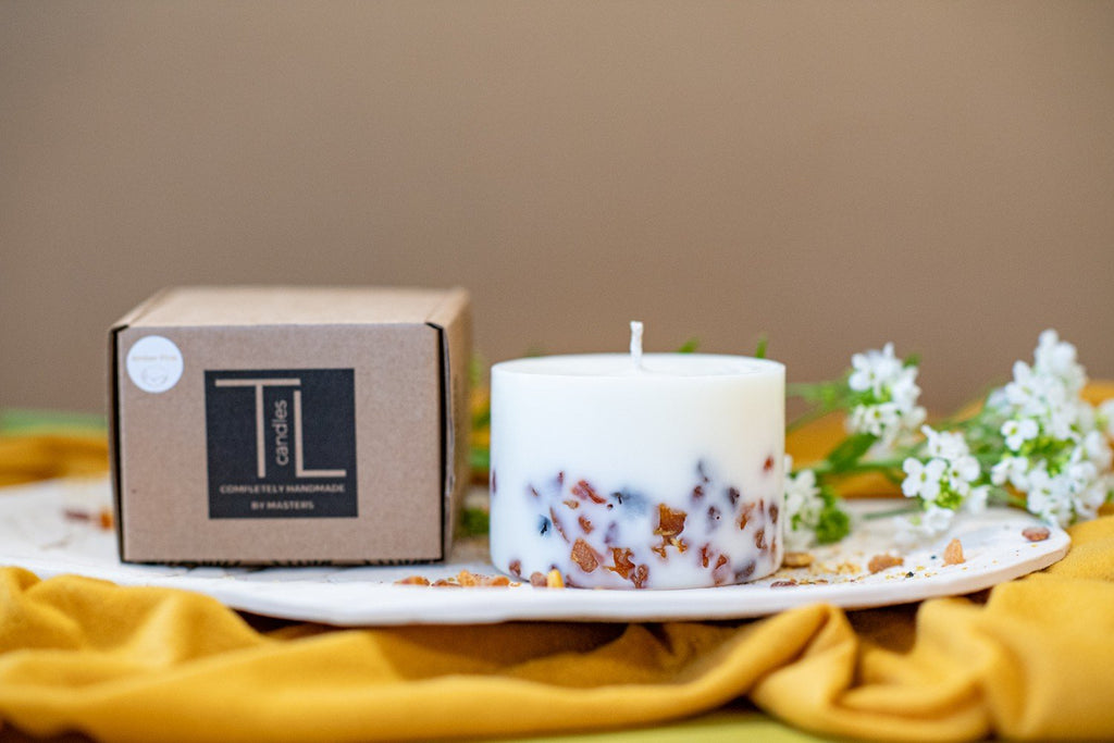9. TL Candles soy wax candle with amber pieces next to branded packaging, showcasing pine scent and natural design