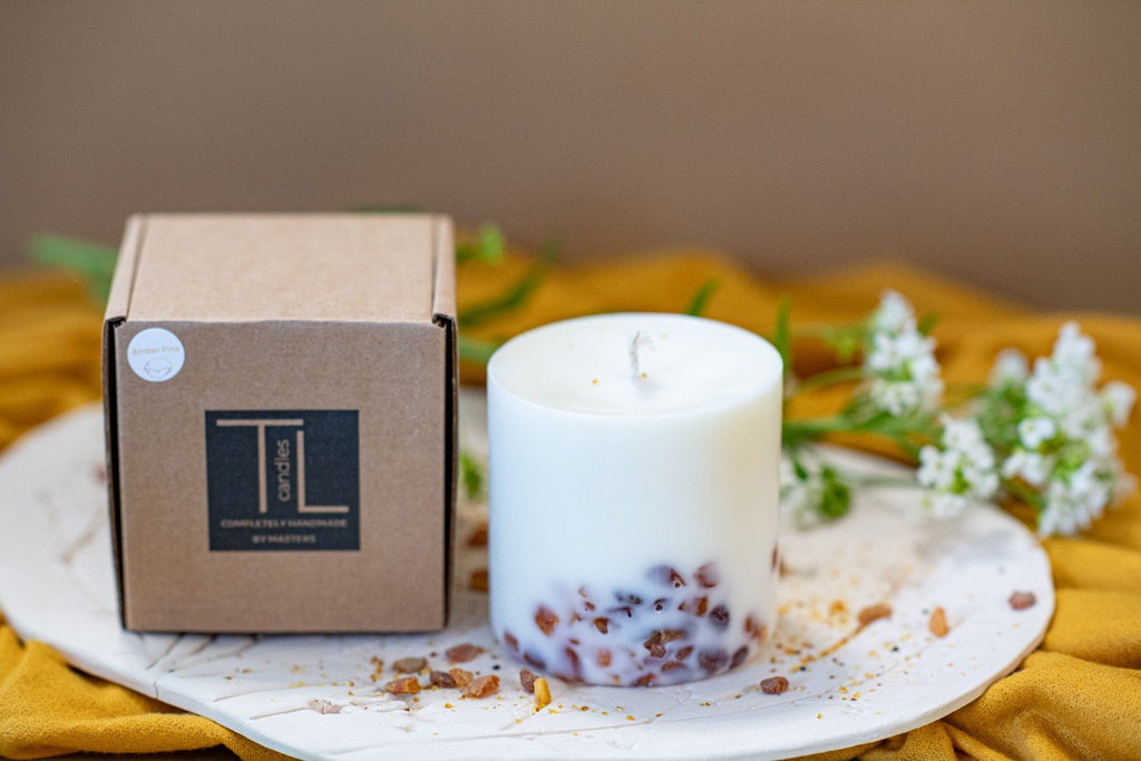 5. TL Candles soy wax candle with amber pieces next to branded packaging, highlighting pine scent and natural design