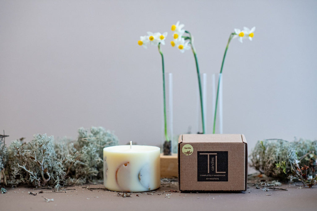 4. Small TL Candles soy wax candle with vanilla scent next to branded packaging, featuring natural decor