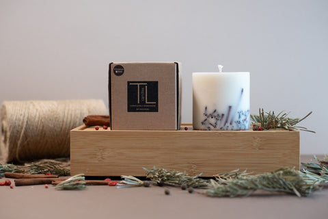 3. TL Candles packaging with white soy wax candle, displayed on wooden tray with natural elements