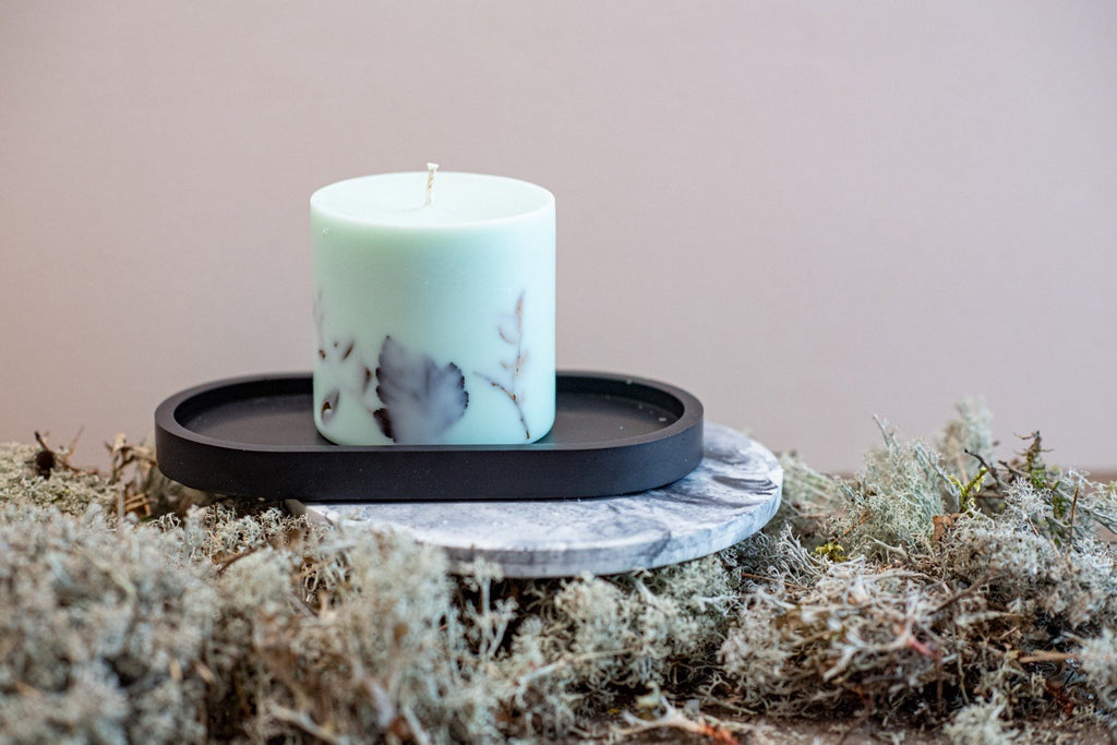 4. Close-up of mint green soy wax candle with forest scent on a black tray, featuring natural moss
