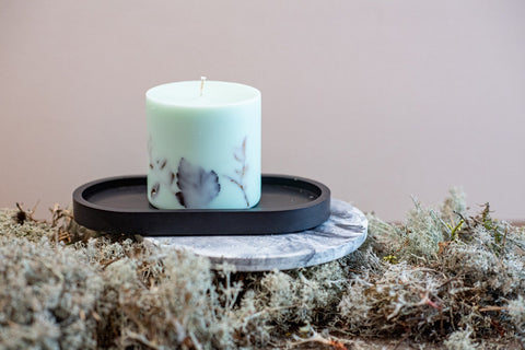 4. Close-up of mint green soy wax candle with forest scent on a black tray, featuring natural moss
