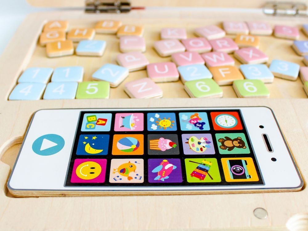 3. Close-up of Ecotoys play phone with colorful app icons, surrounded by pastel magnetic letters