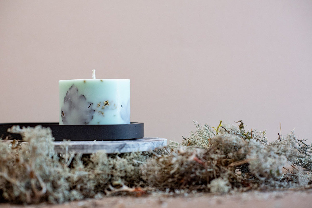 1. Hand-made mint green soy wax candle with forest scent, surrounded by natural moss, displayed on a black tray