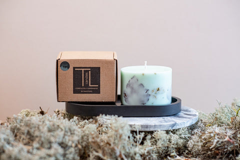 3. Mint green soy wax candle with forest scent and TL Candles box on a black tray, surrounded by moss