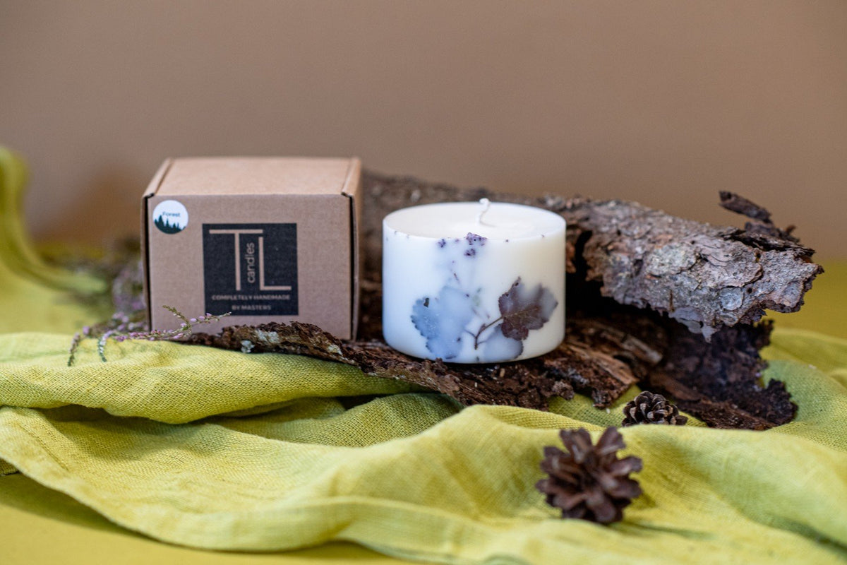 3. Hand-made white soy wax candle with forest scent, shown with TL Candles packaging on bark and green fabric