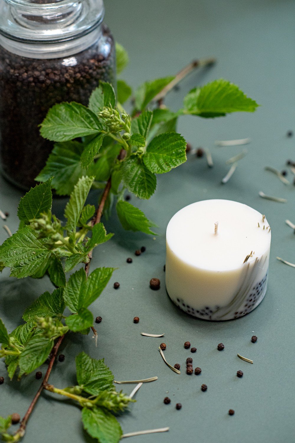 4. Close-up of TL Candles hand-made soy wax candle with juniper scent, surrounded by natural elements