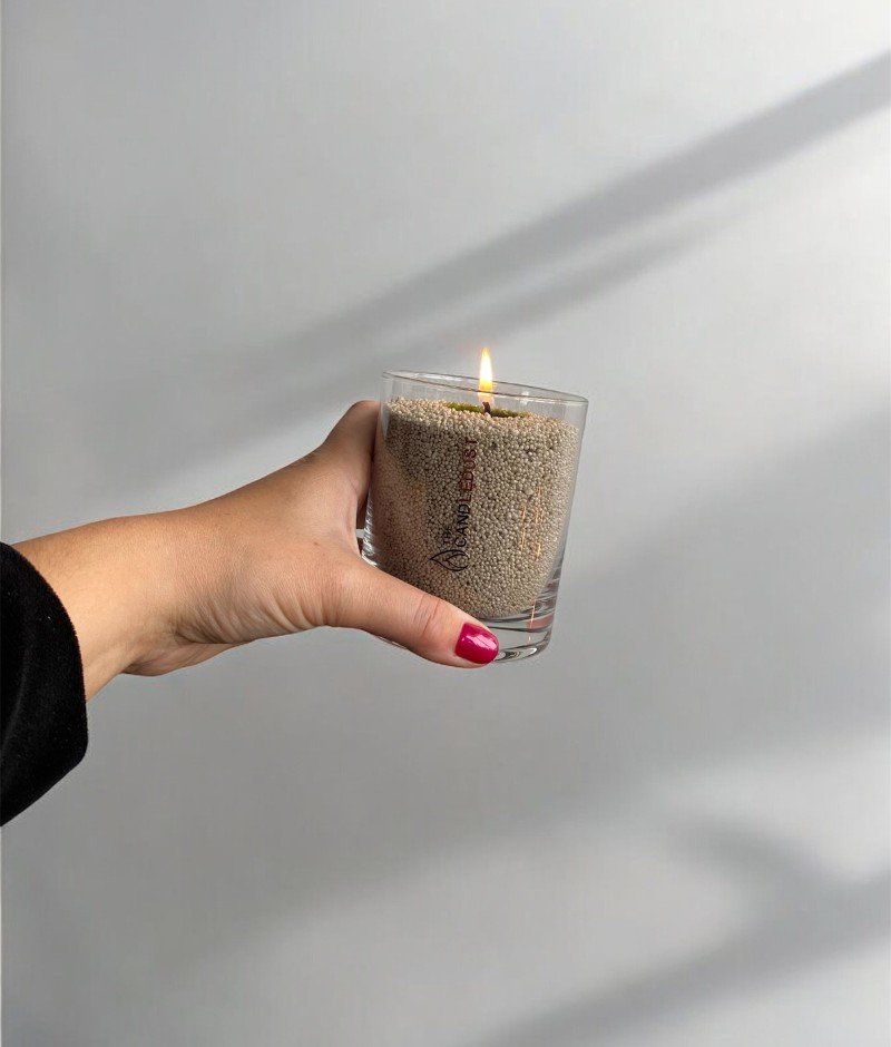 4. Hand holding unscented olive green powder candle by Candledust in glass, lit