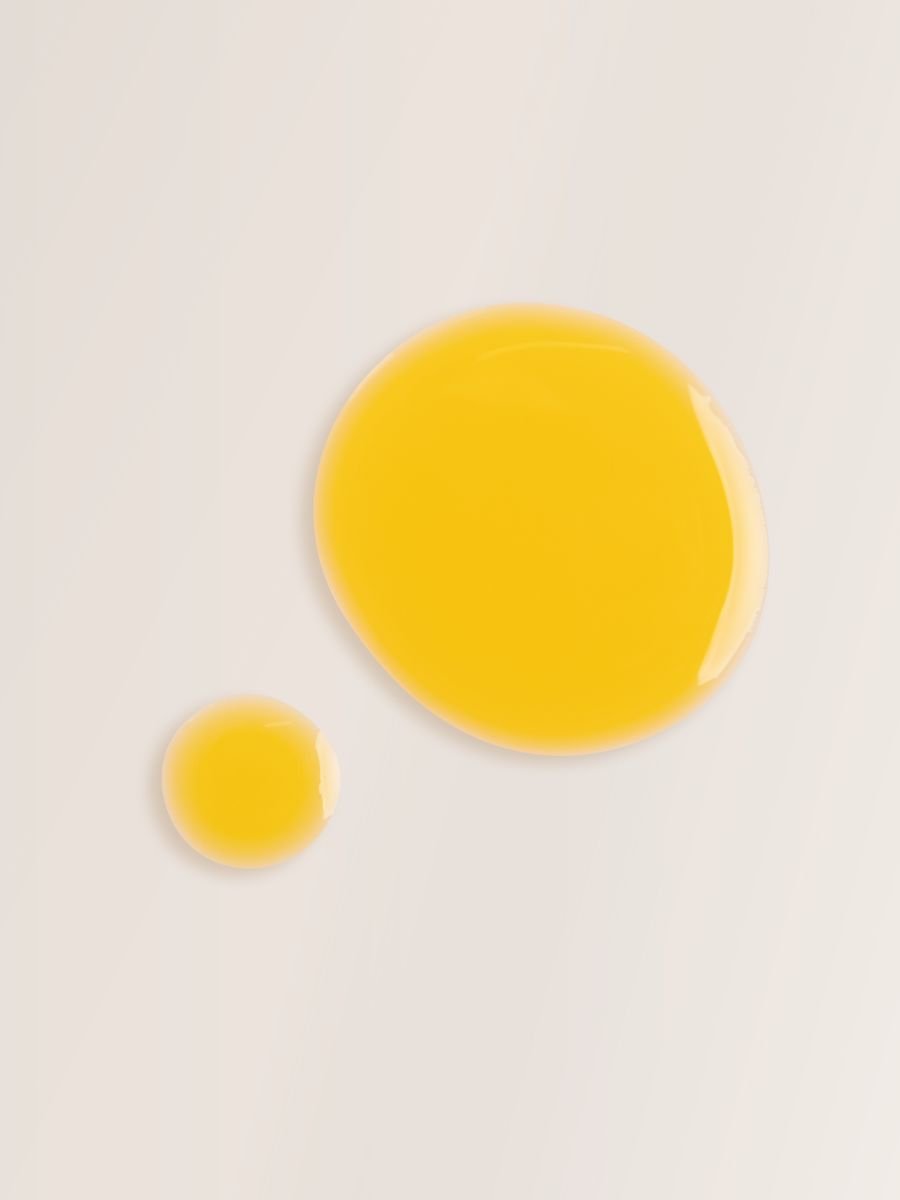 2. Close-up of Magrada Organic Cosmetics Carrot Oil with Rosemary Extract bottle and packaging against a rock