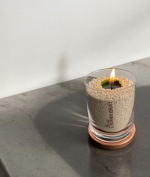 1. Unscented olive green powder candle by Candledust in glass, lit on a stone surface