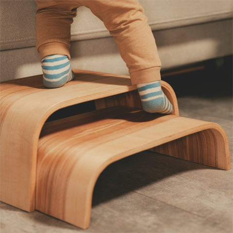 1. Child stepping on wooden step stool with striped socks in a cozy indoor setting