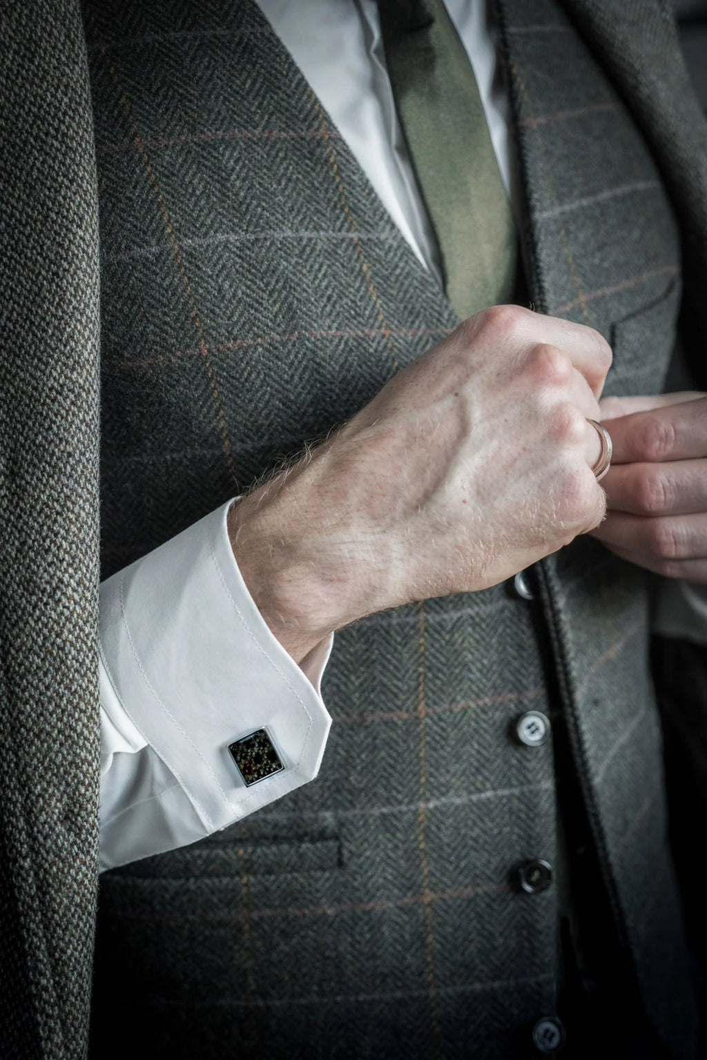 1. Man wearing a grey tweed suit with Eherüs square cufflinks made from dark brown trout leather