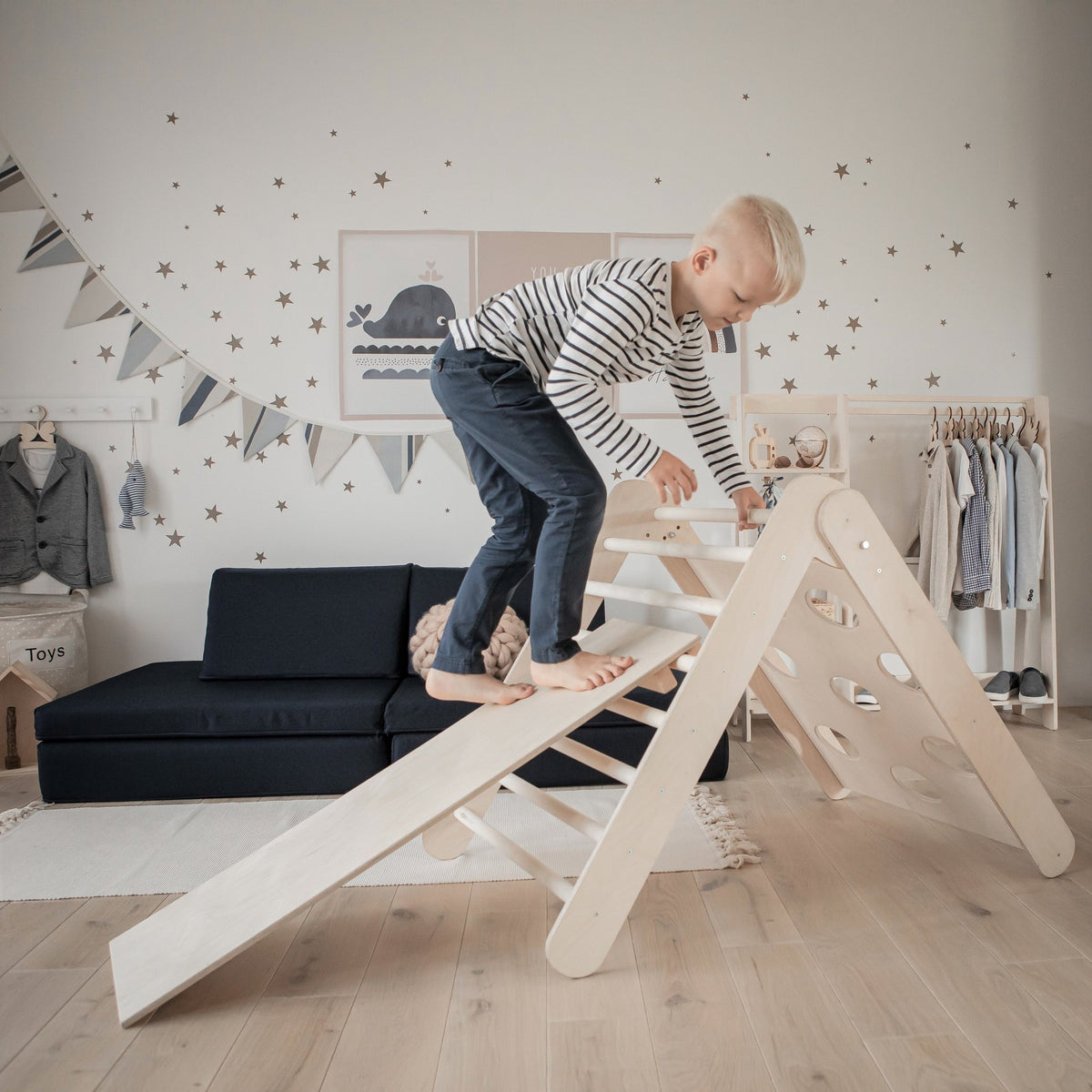 1. Boy climbing Montessori House Bed triangle with ramp in a decorated playroom, showcasing balance and motor skills.
