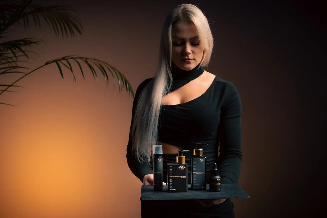 1. Woman holding North Beauty men's skincare set including moisturizing body cream, in a lifestyle setting