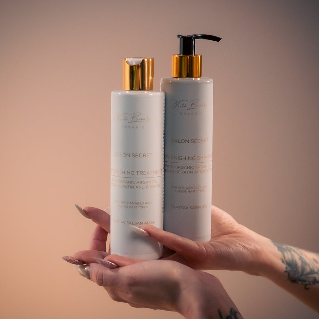 1. Hands holding North Beauty Salon Secret Replenishing Shampoo and Treatment bottles with gold caps against a soft background