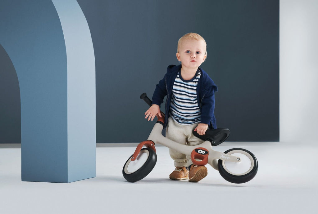 1. Toddler with beige Kinderkraft TOVE balance bike in modern indoor setting