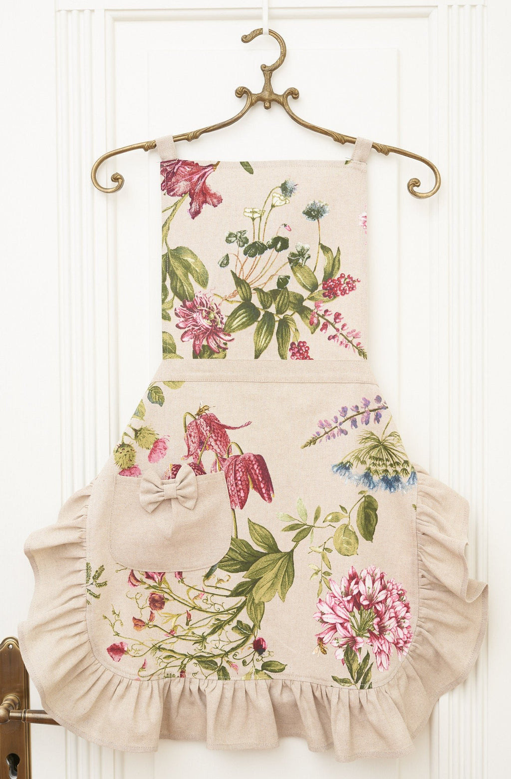 3. Studio shot of Hortensias Home Botanico apron with floral print, ruffles, and pocket on hanger