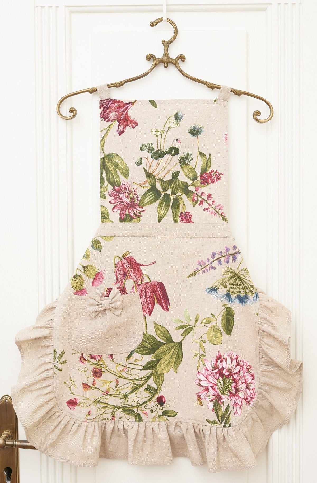 3. Studio shot of Hortensias Home Botanico apron with floral print, ruffles, and pocket on hanger