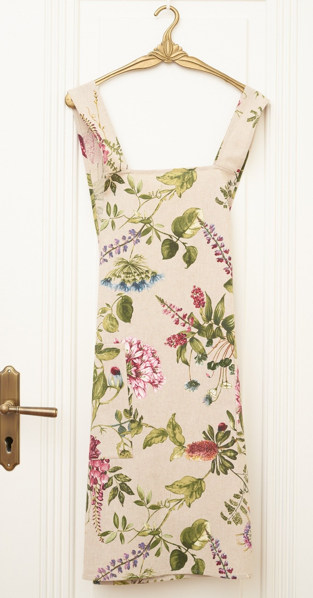 3. Studio shot of Hortensias Home Botanico floral apron with crossed straps on hanger