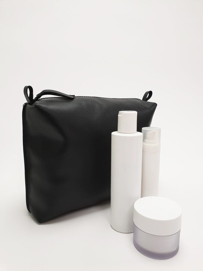 3. Zelma Kraft large black leather cosmetic bag with white cosmetic bottles, showing spaciousness