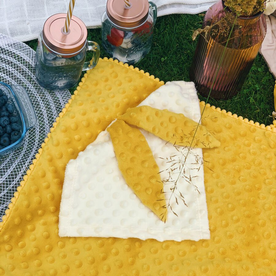 2. Mustard 2in1 blanket with baby comforter laid on grass, showing textured bubbles and plush Milky fabric