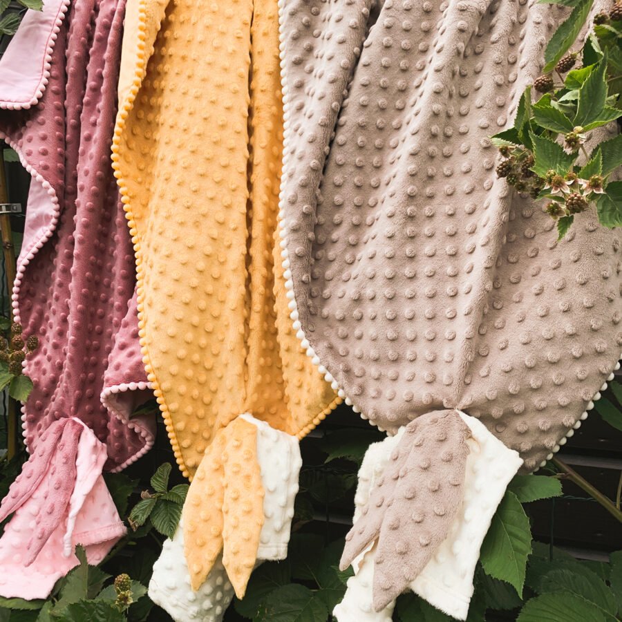 4. Hanging mustard, pink, and beige 2in1 blankets with baby comforters, showing textured bubble design