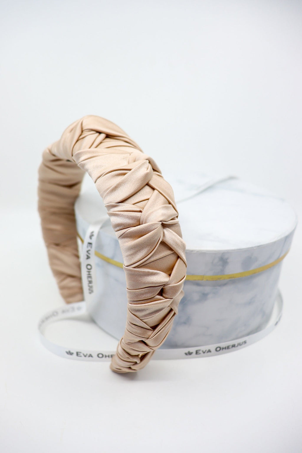 2. Eva Oherjus Jenna Mulberry Silk Knotted Headband in light beige displayed on luxury hat box, showcasing braided design