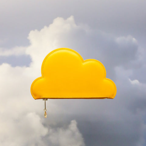 1. Tairi Roosve Leather Cloud Purse in mustard, floating against a cloudy sky, showcasing its unique shape and sustainable design