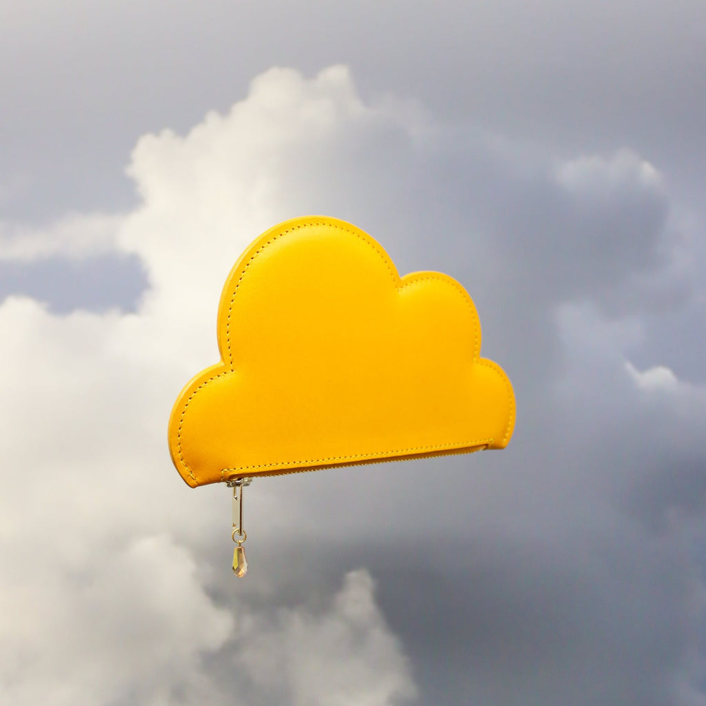 2. Side view of Tairi Roosve mustard Leather Cloud Purse with Excella Zip and Swarovski crystal detail, set against a cloudy backdrop