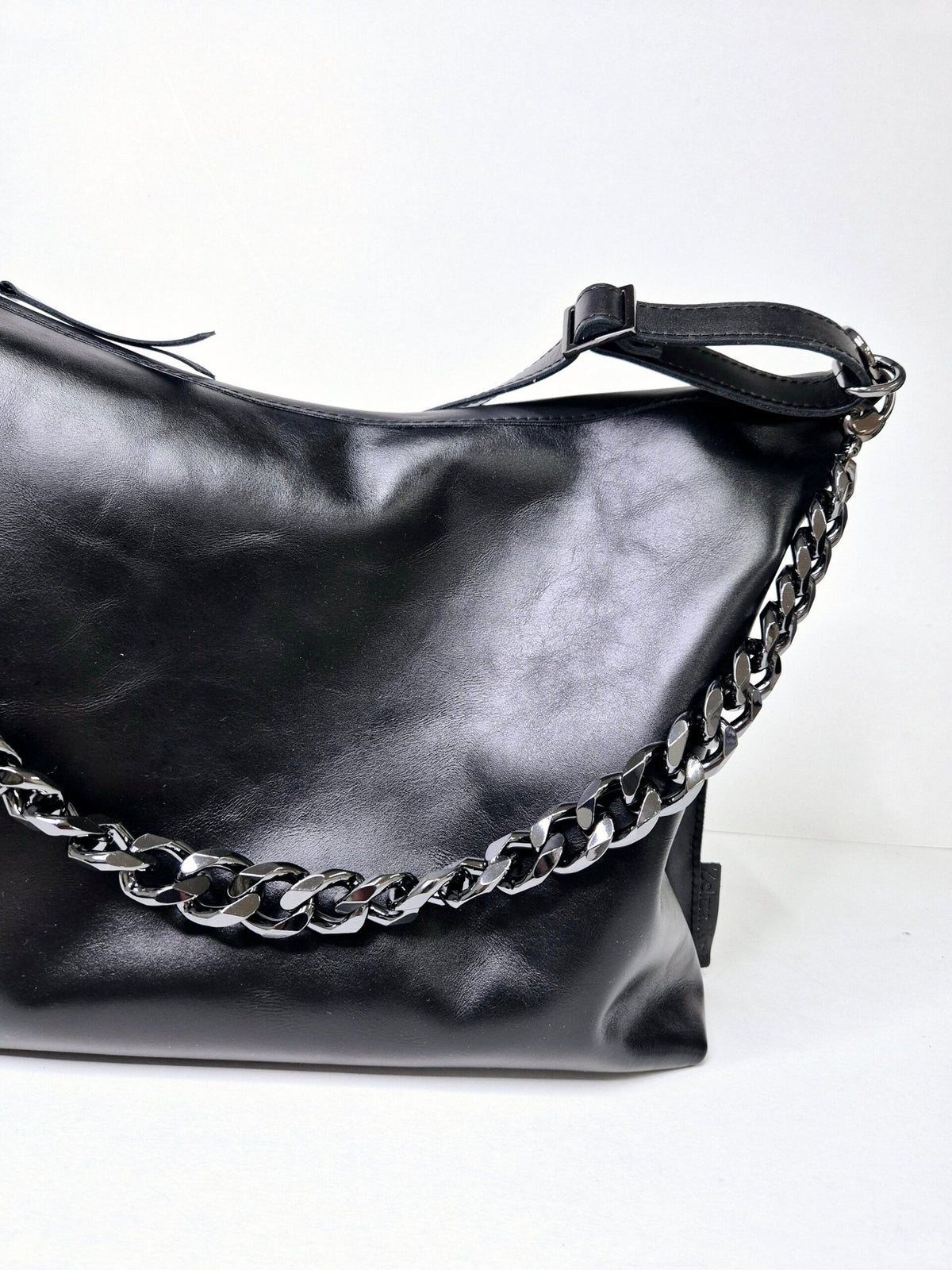 4. Woman wearing Zelma Kraft black leather hobo bag with gold chain strap, shown from the back