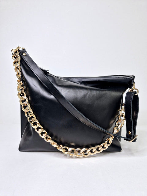 1. Woman wearing Zelma Kraft black leather hobo bag with metallic chain strap, styled for a chic look