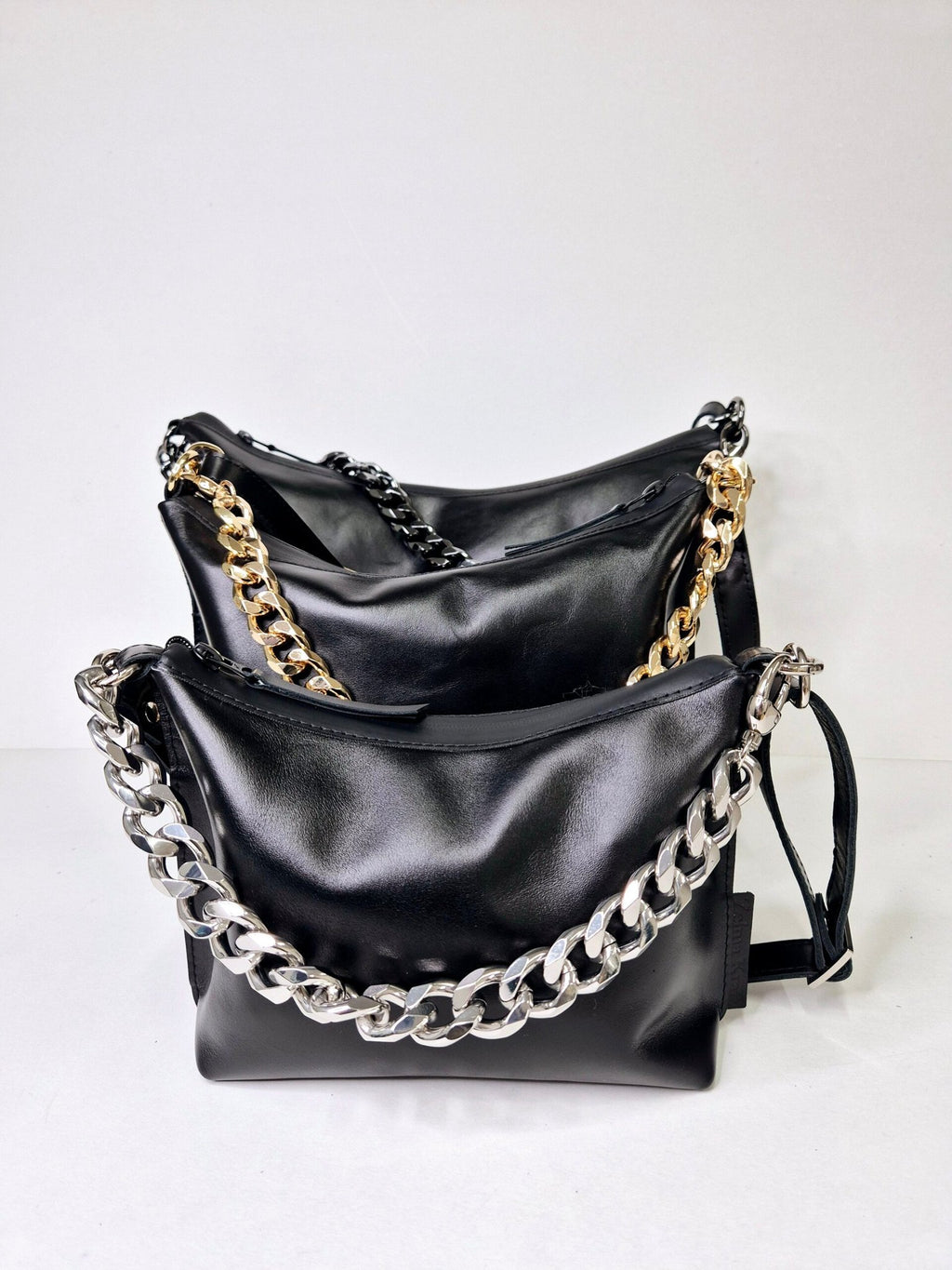 9. Studio shot of two Zelma Kraft black leather hobo bags with gold and silver chains