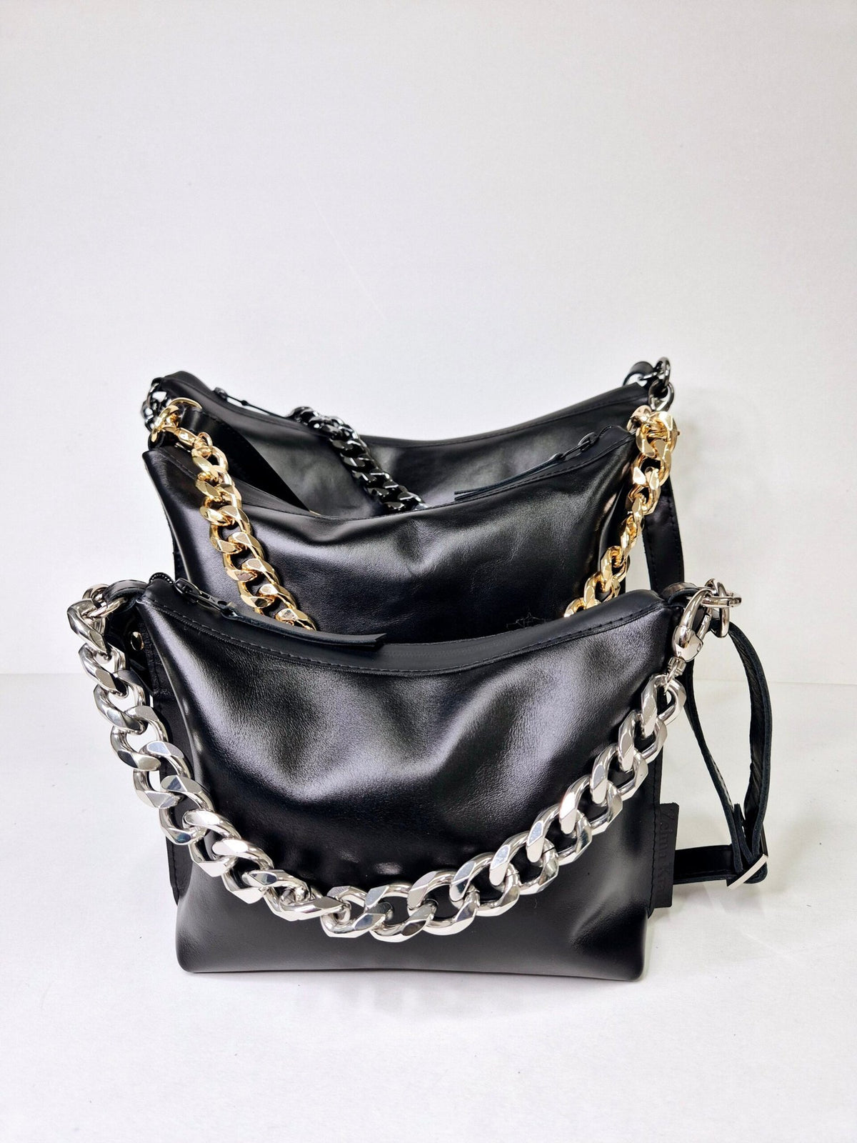9. Studio shot of two Zelma Kraft black leather hobo bags with gold and silver chains